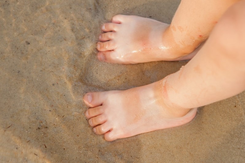 Zongebruinde kindervoetjes op het strand